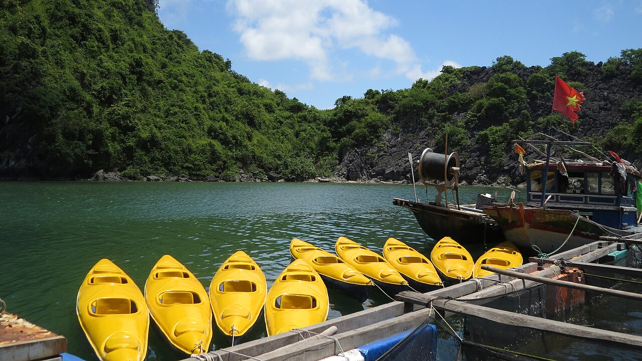 Yellow kayaks moored beside a boat and limestone hills near Cat Ba