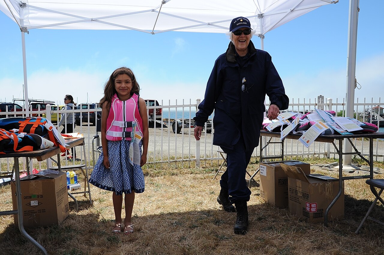 Child wearing a properly fastened child-sized life jacket at a boating safety demonstration