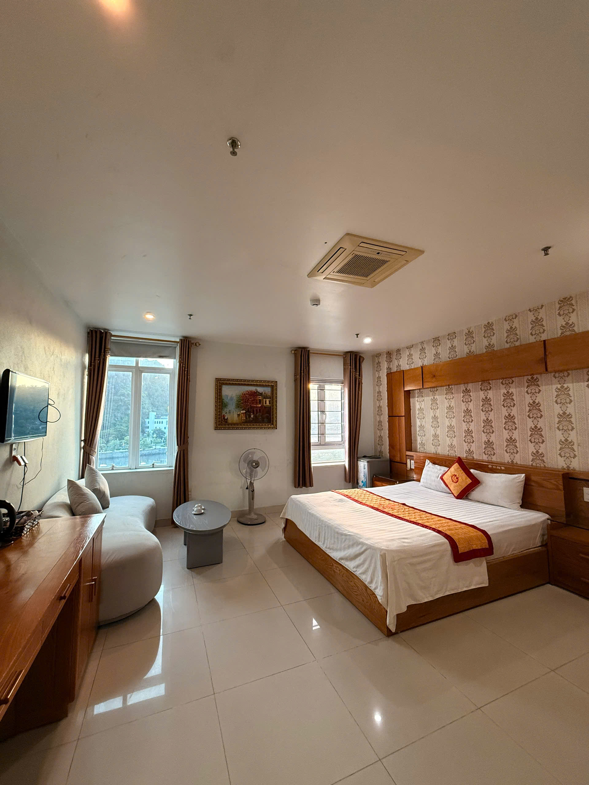 A double hotel room with two windows, a sofa and a tea table