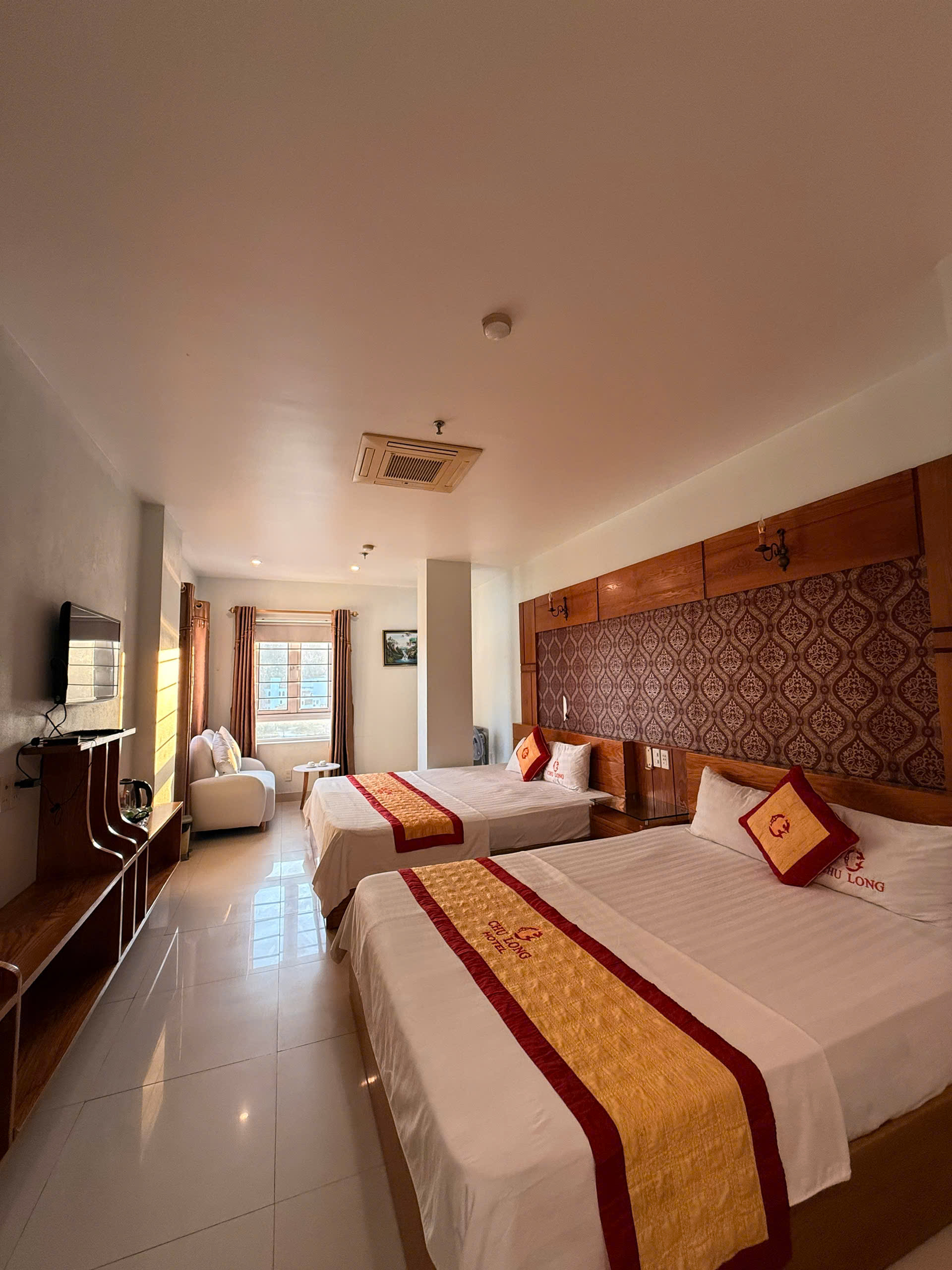 Two beds with red and gold runners and a seating area by the window