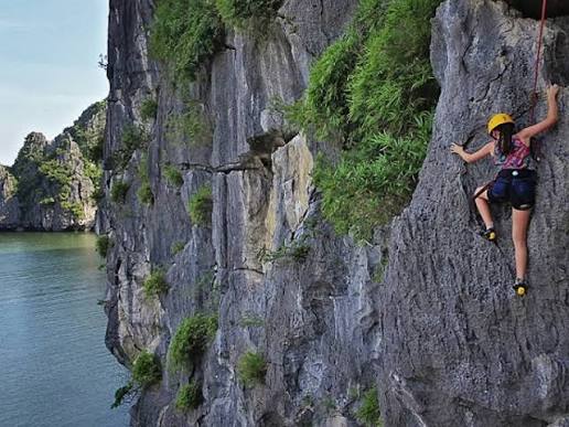 A roped climber on a limestone wall overlooking the sea and islands